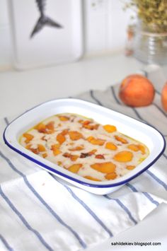 a bowl of food sitting on top of a table next to oranges and a vase