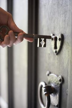 a person is opening the door with a key in their hand and there are two locks on both sides