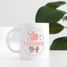 a white coffee mug sitting on top of a table next to a potted plant