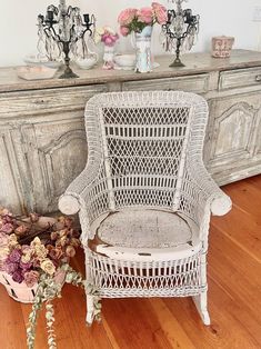 a white wicker chair sitting in front of a dresser with vases on it