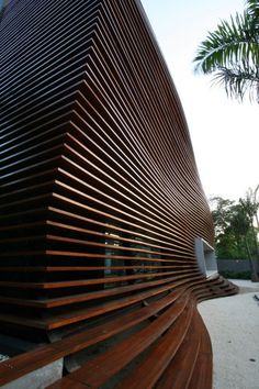 a large wooden structure sitting on top of a cement ground next to a palm tree