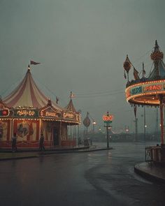 an amusement park at night with lights on the carousels and rides in the rain