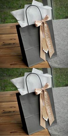 two bags with ribbons tied to them sitting on top of a wooden table