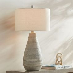 a table lamp sitting on top of a wooden shelf next to a book and some books