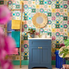 a bathroom with colorful tiles on the wall and sink in front of a blue cabinet