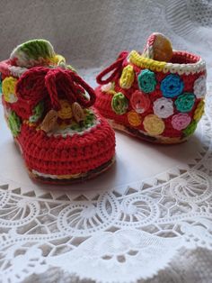 two crocheted baby shoes sitting on top of a white doily covered table