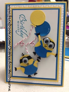 a blue and yellow card with two minion holding balloons