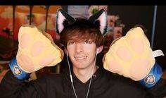 a young man wearing animal ears and holding his hands up in front of his face