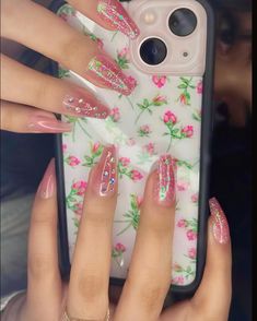 a woman holding up her phone case with pink flowers and glitters on the cover