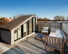 an outdoor deck with two chairs and a small shed roof on the top of a building