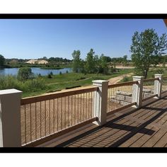 a wooden deck with white railings next to a lake