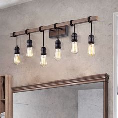 a bathroom light fixture with five bulbs hanging from it's side and a mirror in the background