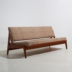 a brown couch sitting on top of a white floor next to a wooden frame bench