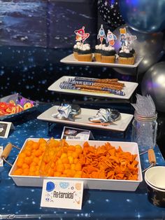 an assortment of desserts and snacks are on display at a space themed birthday party