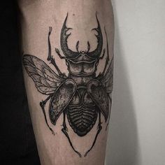 a black and white tattoo of a bug with horns