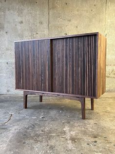 a large wooden cabinet sitting on top of a cement floor next to a concrete wall