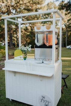 an ice cream cart with plates and cups on it in the grass near some trees