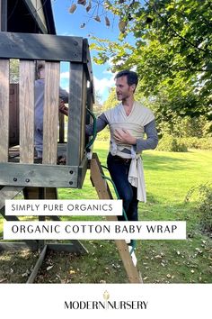 A father using The Simply Pure Organic Cotton Baby Wrap to hold their baby up while playing with his other kid on a playground set. Baby Carrier