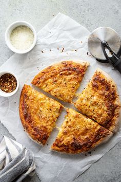 a sliced pizza sitting on top of a piece of paper next to some condiments