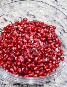 pomegranates in a glass bowl on a marble countertop, ready to be cooked