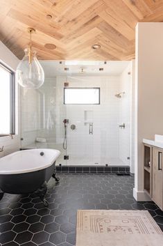 a bathroom with a black and white bathtub sitting next to a sink under a wooden ceiling