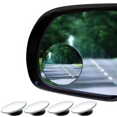 the rear view mirror has four mirrors on it and is reflecting an image of trees