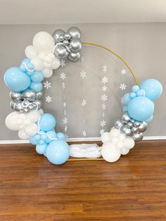 a balloon arch with snowflakes and balloons on the floor in front of a wall