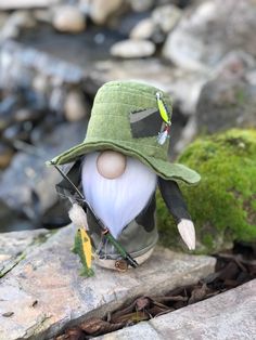 a small gnome with a fishing rod and hat on top of a rock next to a stream