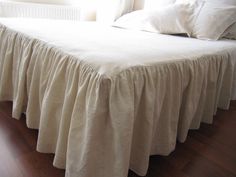 the bed is made with white linens and has a ruffled bedskirt