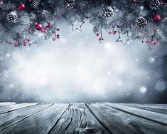 an empty wooden table with christmas decorations on it and snow flakes in the background