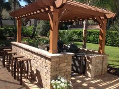 an outdoor kitchen with bar stools and grill