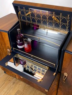 an open wooden cabinet with bottles and glasses in it on top of a hard wood floor