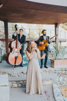 a woman in a long dress standing on steps with her hands out to someone playing the guitar