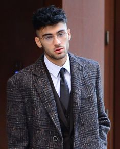 a man in a suit and tie is looking at the camera while he stands outside