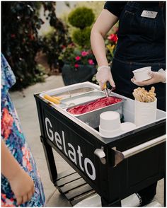 two people are serving themselves food from a gelato cart