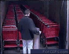 a man standing in front of red chairs with his back to the camera and looking at them