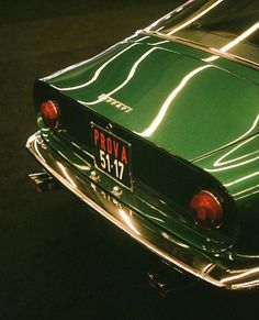 the front end of an old green car with chrome trim and license plate number 517