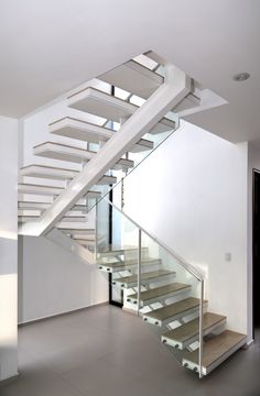 a white staircase with glass balconies and metal handrails in an empty room