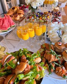 a table filled with lots of food and glasses of orange juice on top of it