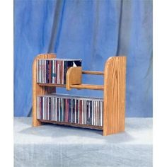 a wooden book shelf with several cd's on it and a blue curtain in the background