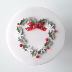 a cake decorated with holly and mistlet leaves in the shape of a heart on top of a white plate