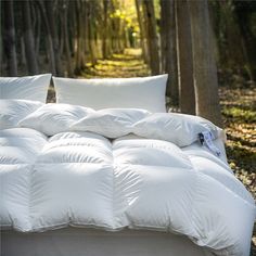 an unmade bed in the woods with white pillows