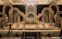 an elaborately decorated room with chandelier and flowers on the wall, in front of a stage