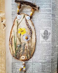 a piece of art made out of an old book with buttons and flowers on it