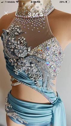 the back of a woman's blue dress with silver beads and jewels on it