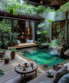 an indoor swimming pool surrounded by greenery and potted plants in the middle of a patio