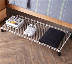 two pairs of shoes are sitting on a wire shelf next to a bed with pillows