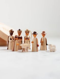 a group of wooden toy figurines standing next to each other on a white surface