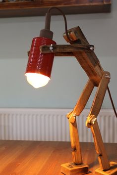 a lamp made out of wooden planks with a red shade on it's head