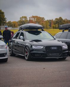 two cars parked in a parking lot with luggage strapped to the roof and on top